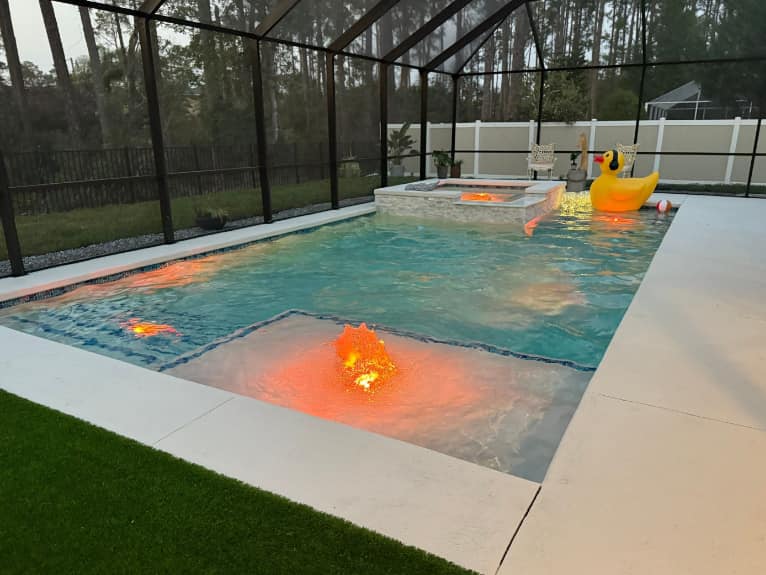 pool with bubblers, water features lit up with pool cage